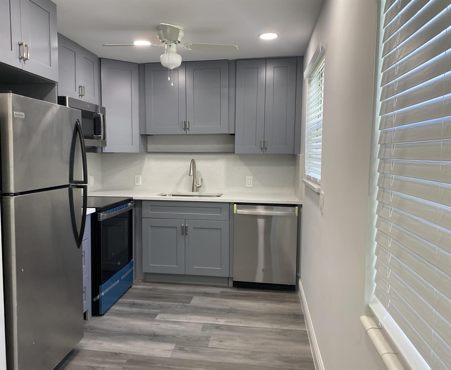 A small kitchen features gray cabinets, stainless steel appliances, and light-colored countertops — 256 Mansfield # G, Boca Raton FL 33434, BOCA RATON, FL