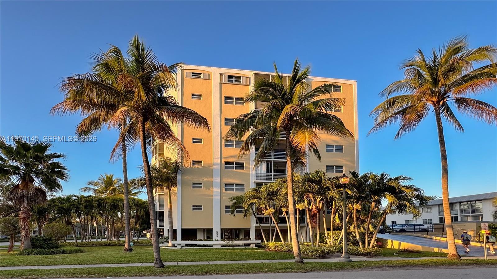 A multi-story yellow apartment building is surrounded by palm trees under a clear blue sky — 555 Crandon Blvd # 82, Key Biscayne FL 33149, KEY BISCAYNE, FL