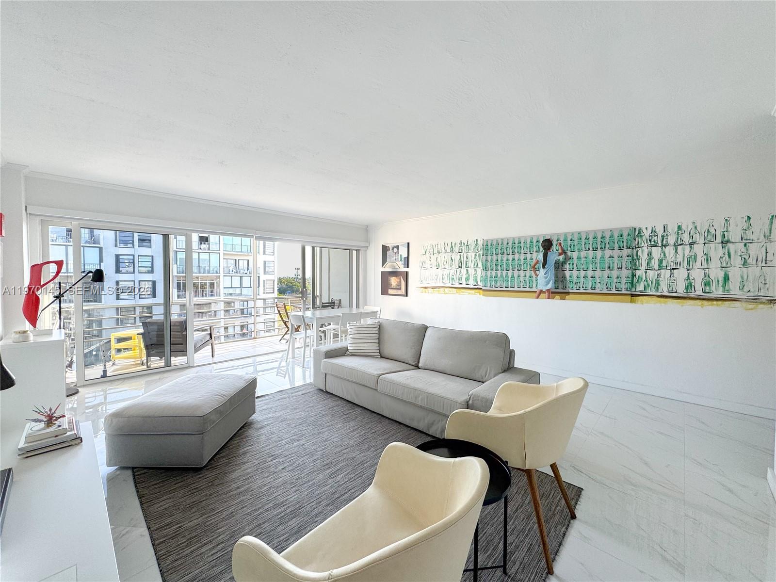 A bright living room features a gray sofa, two cream chairs, and large glass balcony doors — 555 Crandon Blvd # 82, Key Biscayne FL 33149, KEY BISCAYNE, FL