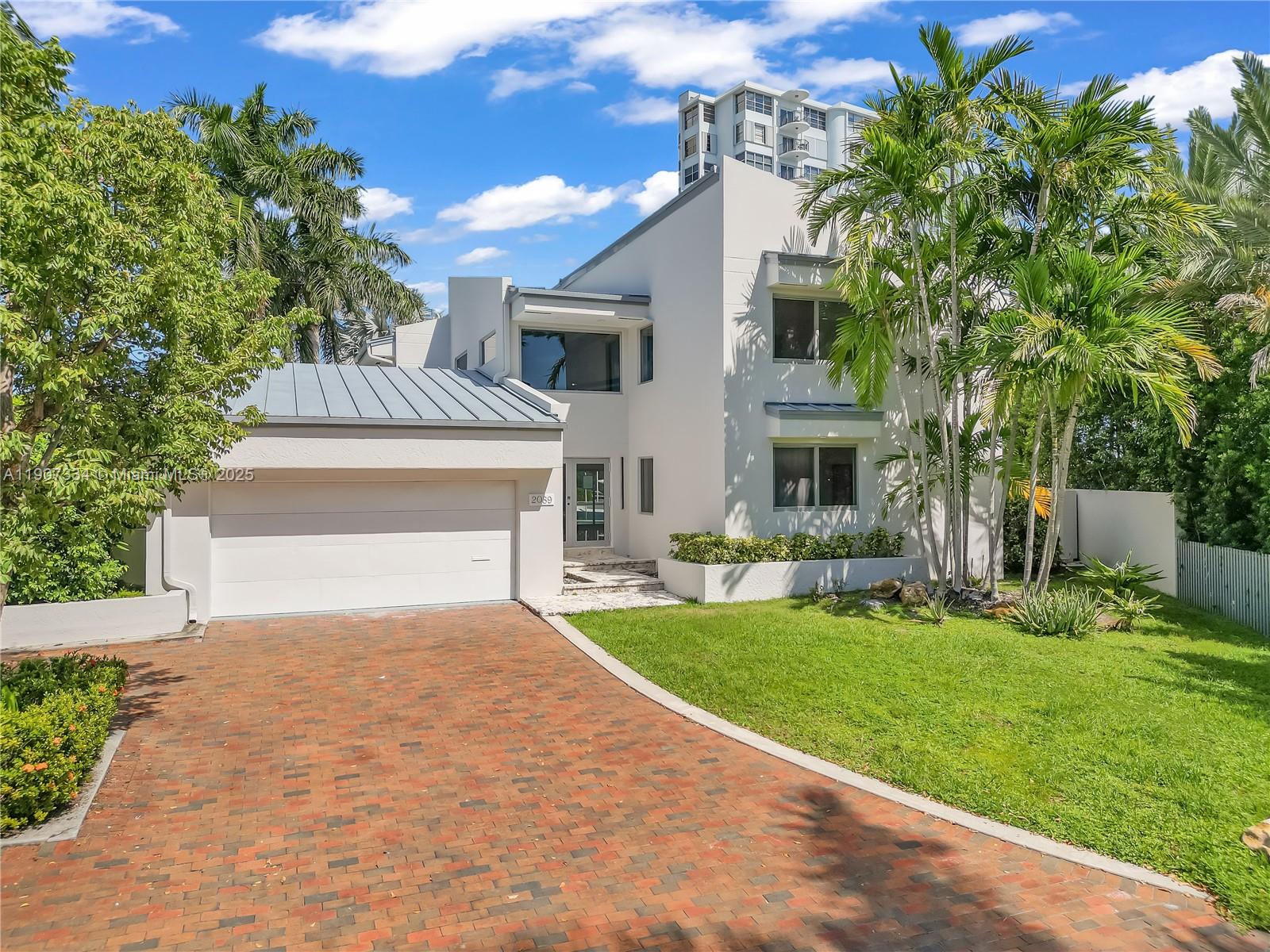 A two-story modern house with a brick driveway, metal roof, and palm trees — 2089 NE 121st Rd, North Miami FL 33181, NORTH MIAMI, FL