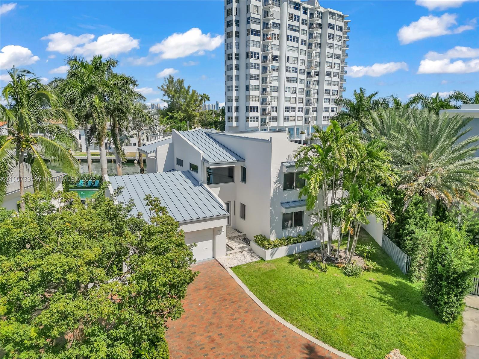 An aerial view of a modern two-story house with a metal roof and brick driveway — 2089 NE 121st Rd, North Miami FL 33181, NORTH MIAMI, FL