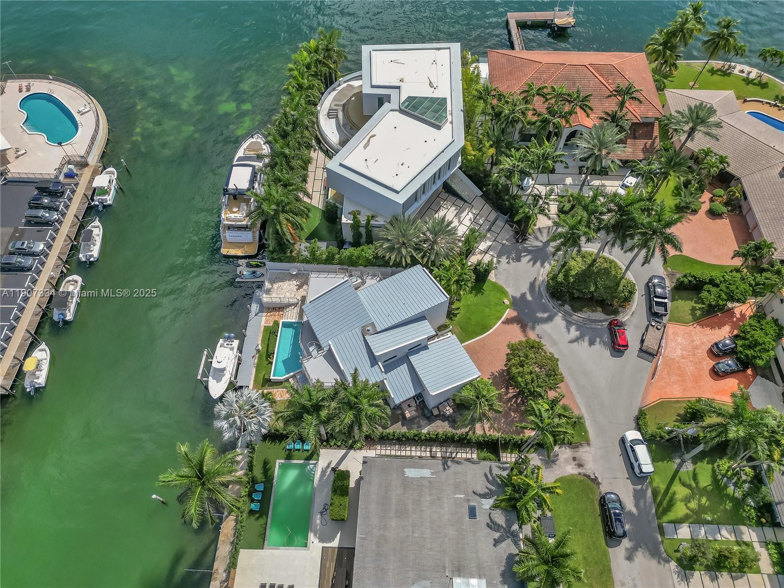 An aerial view shows several waterfront homes with swimming pools, private docks, and parked vehicles — 2089 NE 121st Rd, North Miami FL 33181, NORTH MIAMI, FL