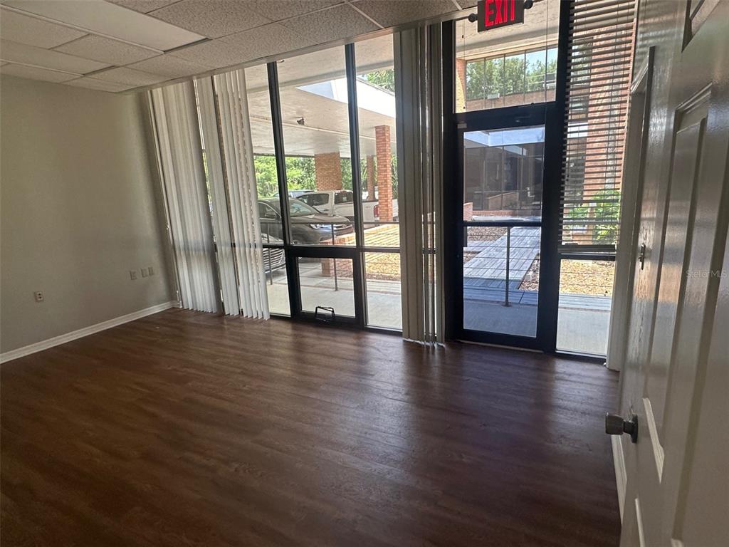 An office space with wood-look flooring, large windows, vertical blinds, and a glass entry door — 2770 NW 43RD STREET UNIT N, GAINESVILLE, FL