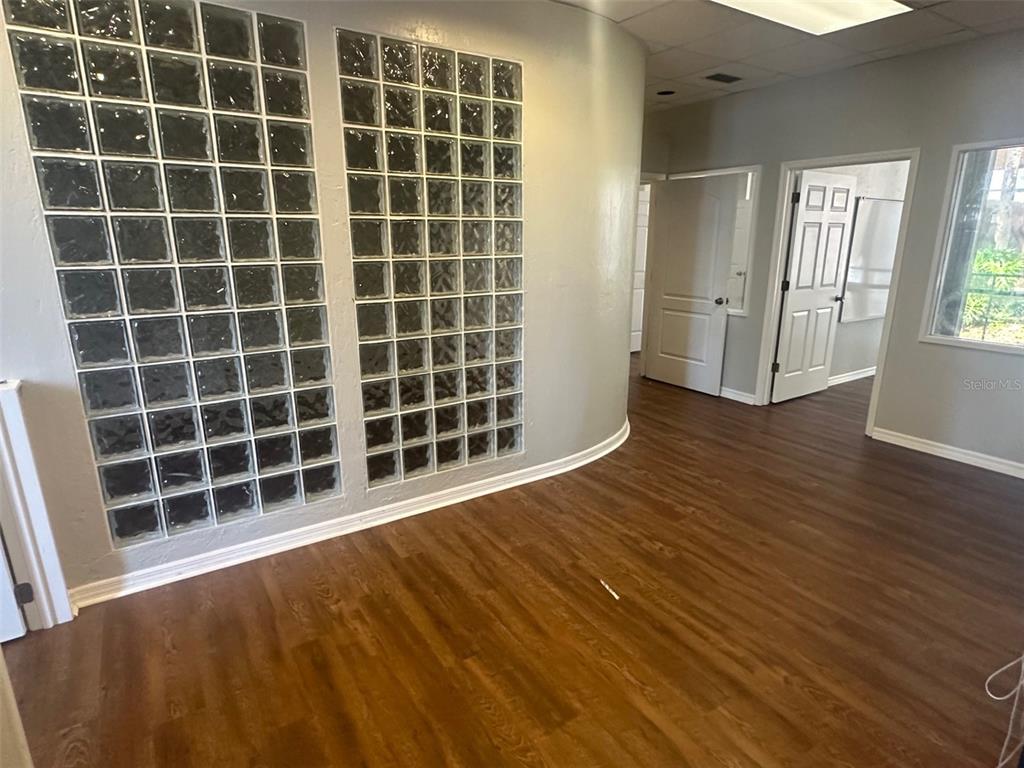 An interior room features wood-look flooring, a curved wall with glass blocks, and two doorways — 2770 NW 43RD STREET UNIT N, GAINESVILLE, FL