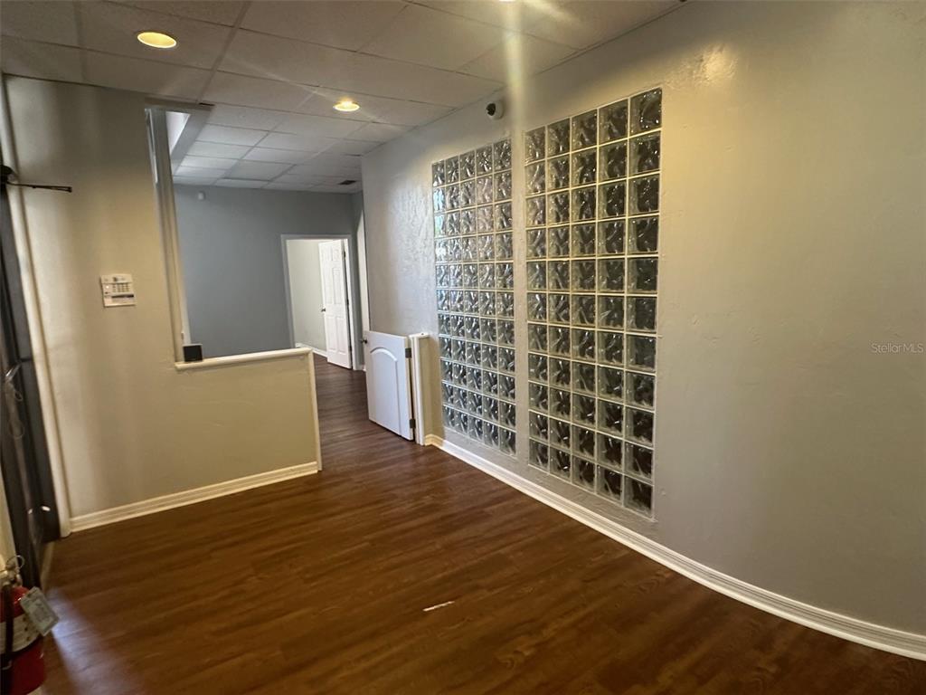 An interior room features wood-look flooring, a glass block wall, and a drop ceiling — 2770 NW 43RD STREET UNIT N, GAINESVILLE, FL