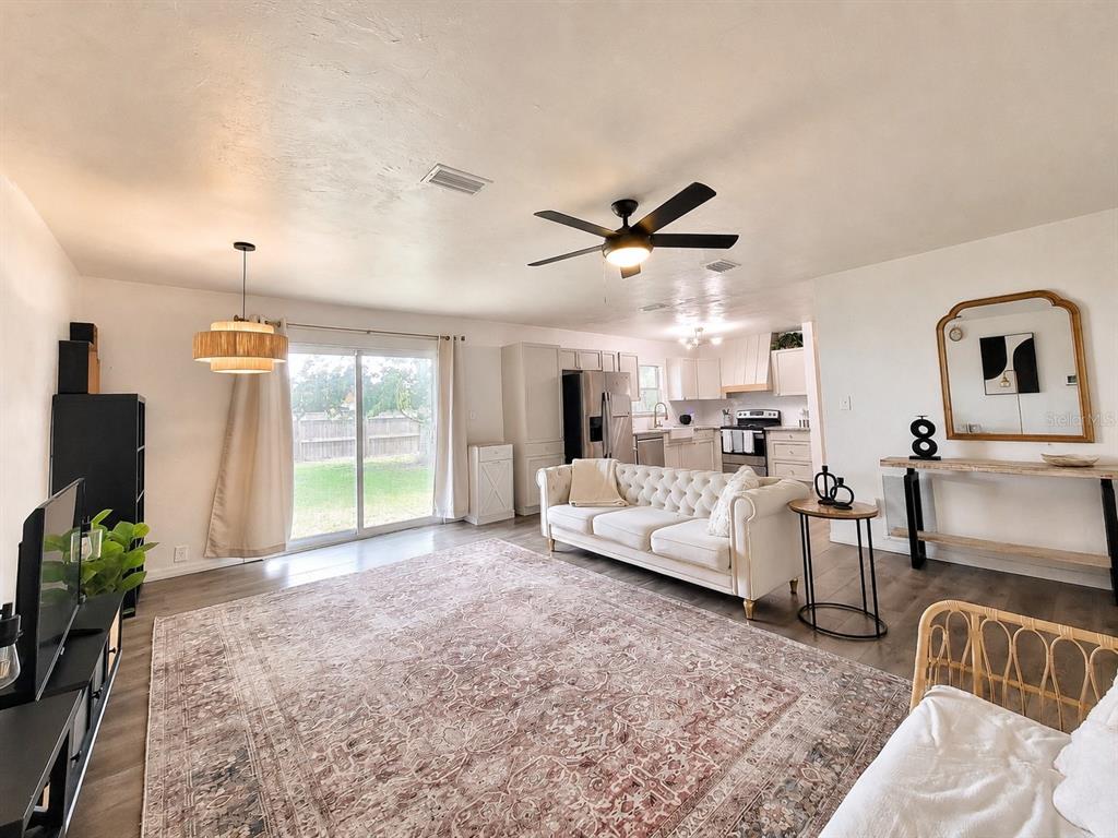 A living room features a tufted white sofa, a large patterned rug, and an open kitchen — 2524 NE 5TH PLACE, GAINESVILLE, FL