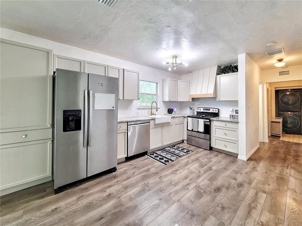 A kitchen features light-colored cabinets, stainless steel appliances, granite countertops, and wood-look flooring — 2524 NE 5TH PLACE, GAINESVILLE, FL
