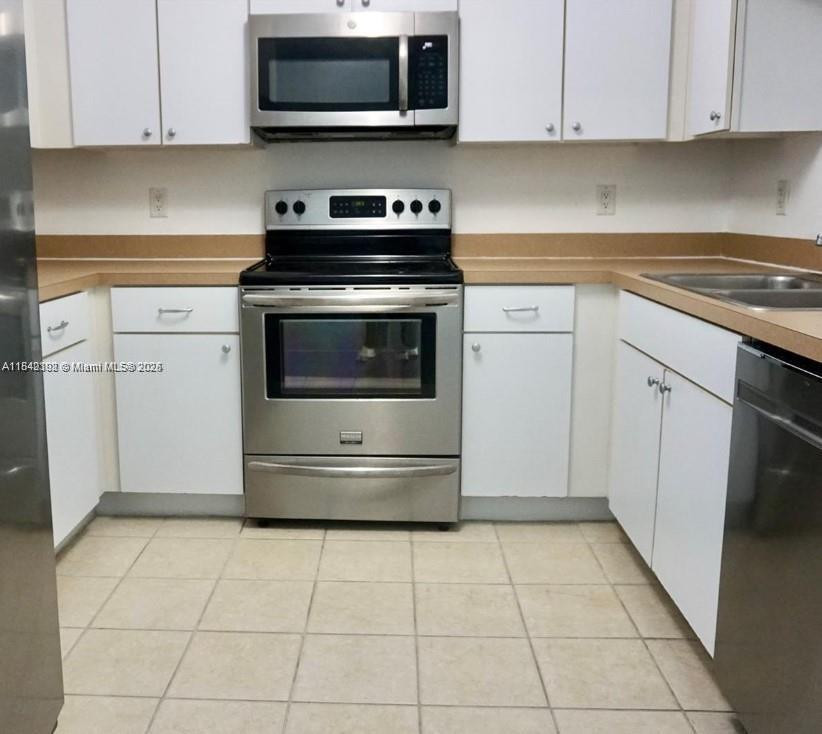 A kitchen features white cabinets, stainless steel appliances, and tan countertops over tiled flooring — 1250 S Miami Ave # 2006, Miami FL 33130, MIAMI, FL