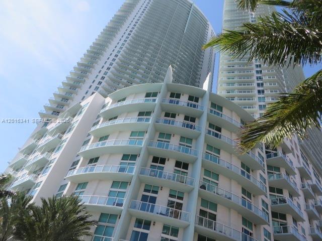 A low-angle view of a modern high-rise residential building with curved balconies and glass railings — 1900 N Bayshore Dr # 1707, Miami FL 33132, MIAMI, FL