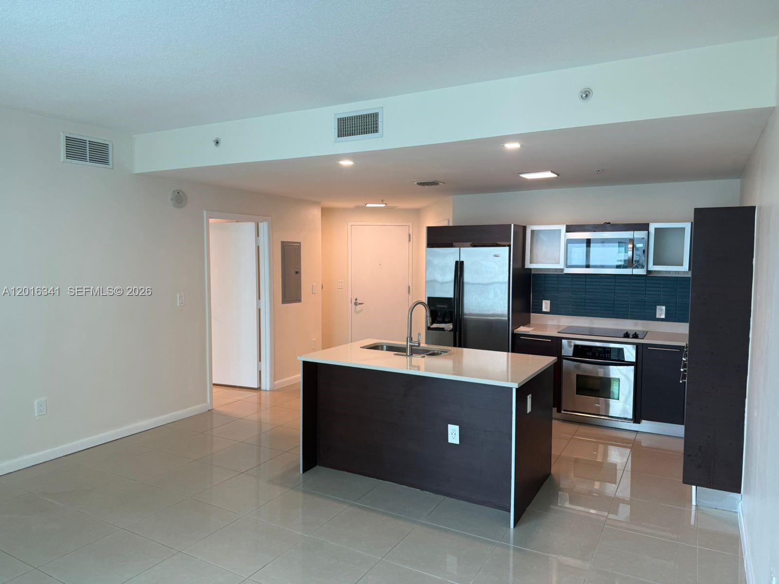 A kitchen with dark cabinets, stainless steel appliances, and a central island with a sink — 1900 N Bayshore Dr # 1707, Miami FL 33132, MIAMI, FL