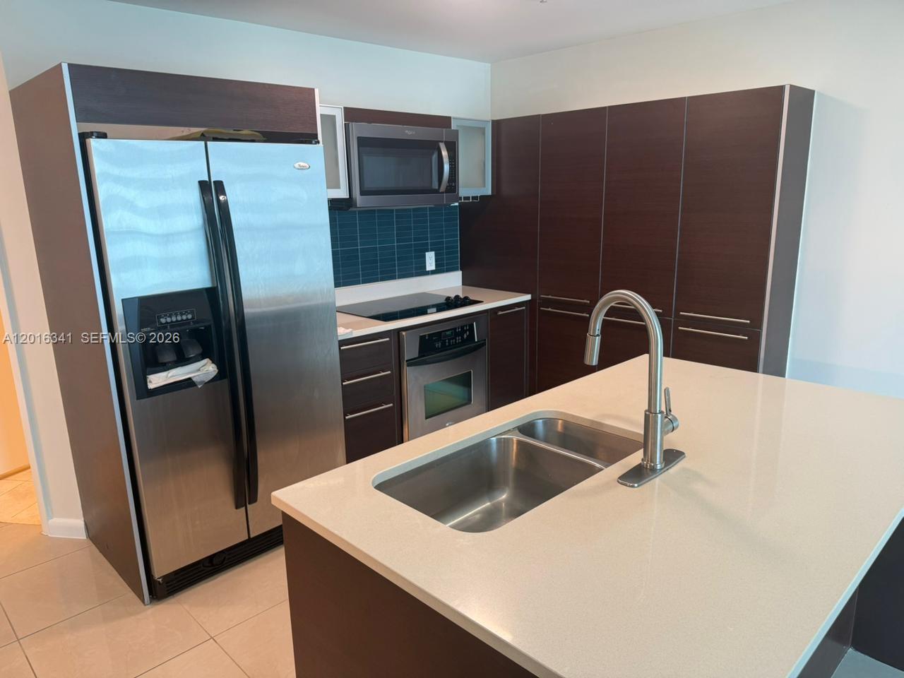 A modern kitchen features dark wood cabinetry, stainless steel appliances, and a central island — 1900 N Bayshore Dr # 1707, Miami FL 33132, MIAMI, FL
