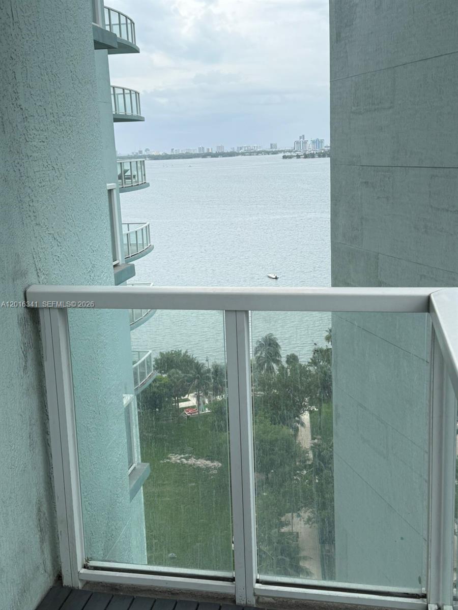 A balcony view overlooks a body of water and a park with palm trees — 1900 N Bayshore Dr # 1707, Miami FL 33132, MIAMI, FL