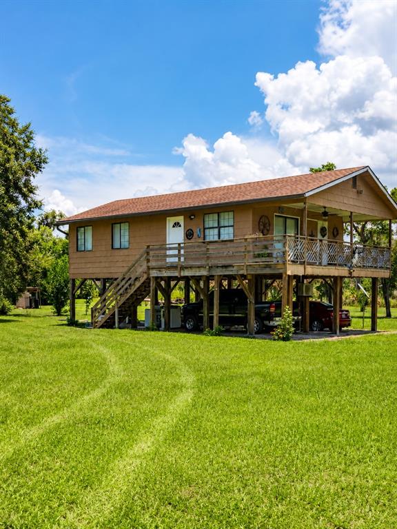 An elevated, brown-sided house with a wooden deck and stairs sits on a grassy lot — 988 FAZZINI DR, FROSTPROOF, FL