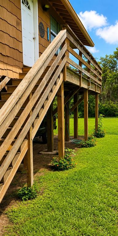 An exterior view of a house with a wooden staircase leading to an elevated deck — 988 FAZZINI DR, FROSTPROOF, FL