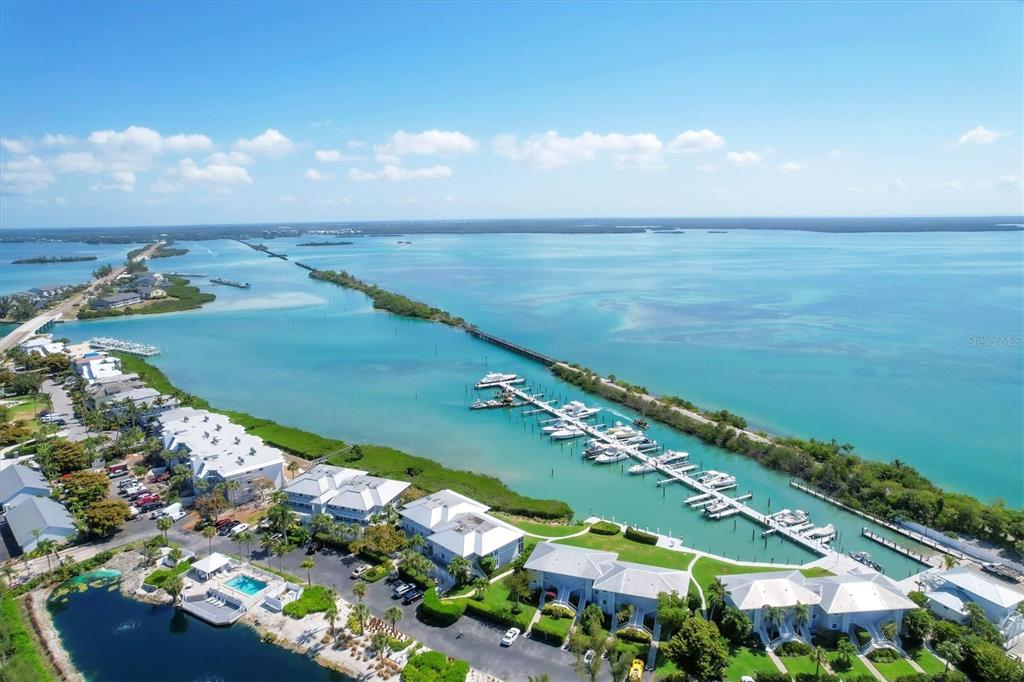 An aerial view shows a waterfront condominium complex with a boat dock and marina — 5820 GASPARILLA ROAD UNIT SLIP #49, BOCA GRANDE, FL