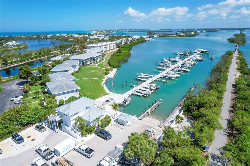 An aerial view shows a marina with docked boats next to multi-story residential buildings — 5820 GASPARILLA ROAD UNIT SLIP #49, BOCA GRANDE, FL