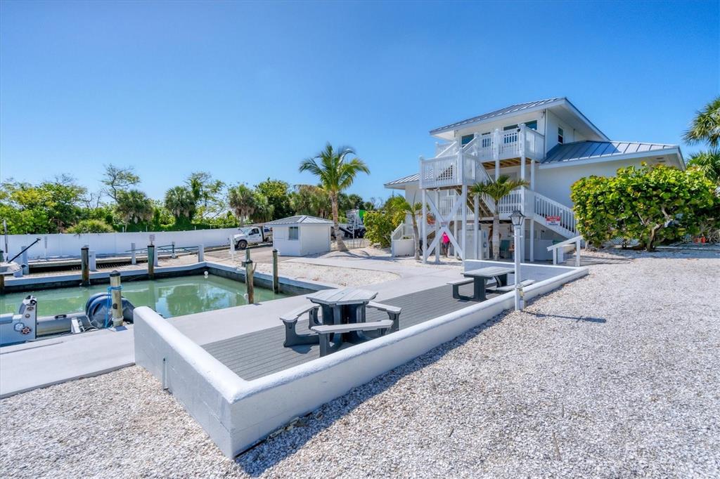 A white house with a metal roof stands next to a boat slip and patio — 5820 GASPARILLA ROAD UNIT SLIP #49, BOCA GRANDE, FL