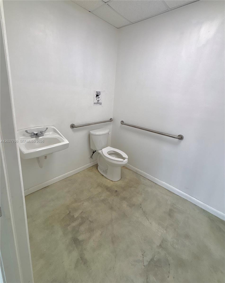 This accessible restroom features a white toilet, a wall-mounted sink, and metal grab bars — 6741 SW 8th St # 6747, Miami FL 33144, MIAMI, FL