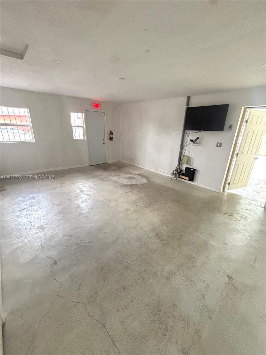 An empty room with concrete floors, white walls, a mounted television, and two doors — 6741 SW 8th St # 6747, Miami FL 33144, MIAMI, FL