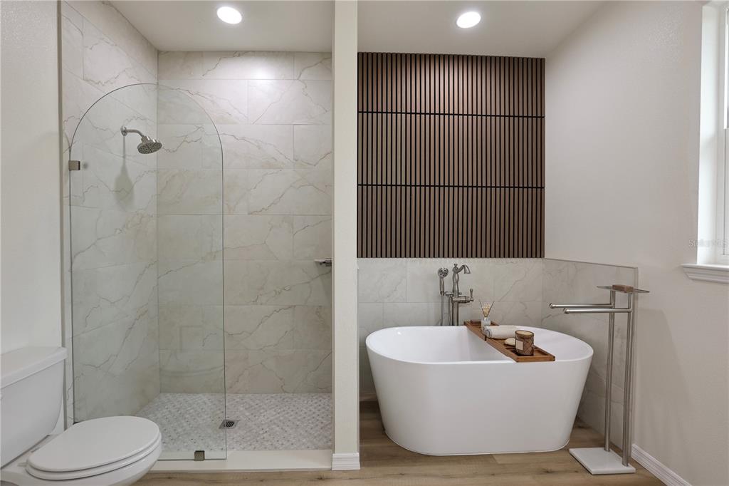 A bathroom features a glass-enclosed shower, a freestanding tub, and a wood-slat accent wall — 7825 PINE GLEN ROAD, SEBRING, FL