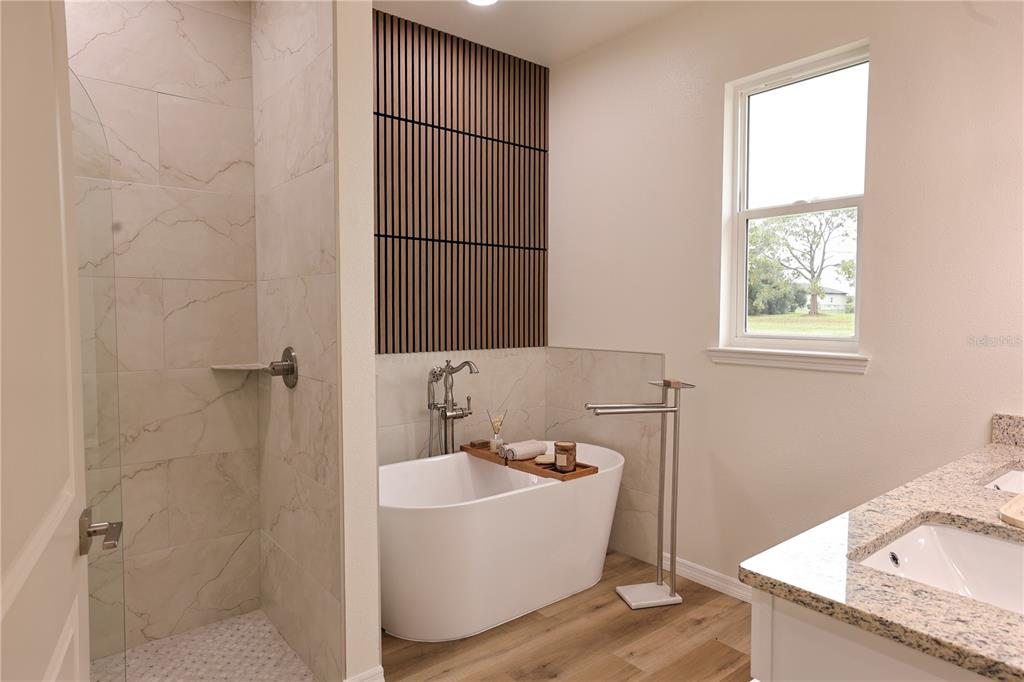 A bathroom features a freestanding tub, a tiled walk-in shower, and a wood-slat accent wall — 7825 PINE GLEN ROAD, SEBRING, FL