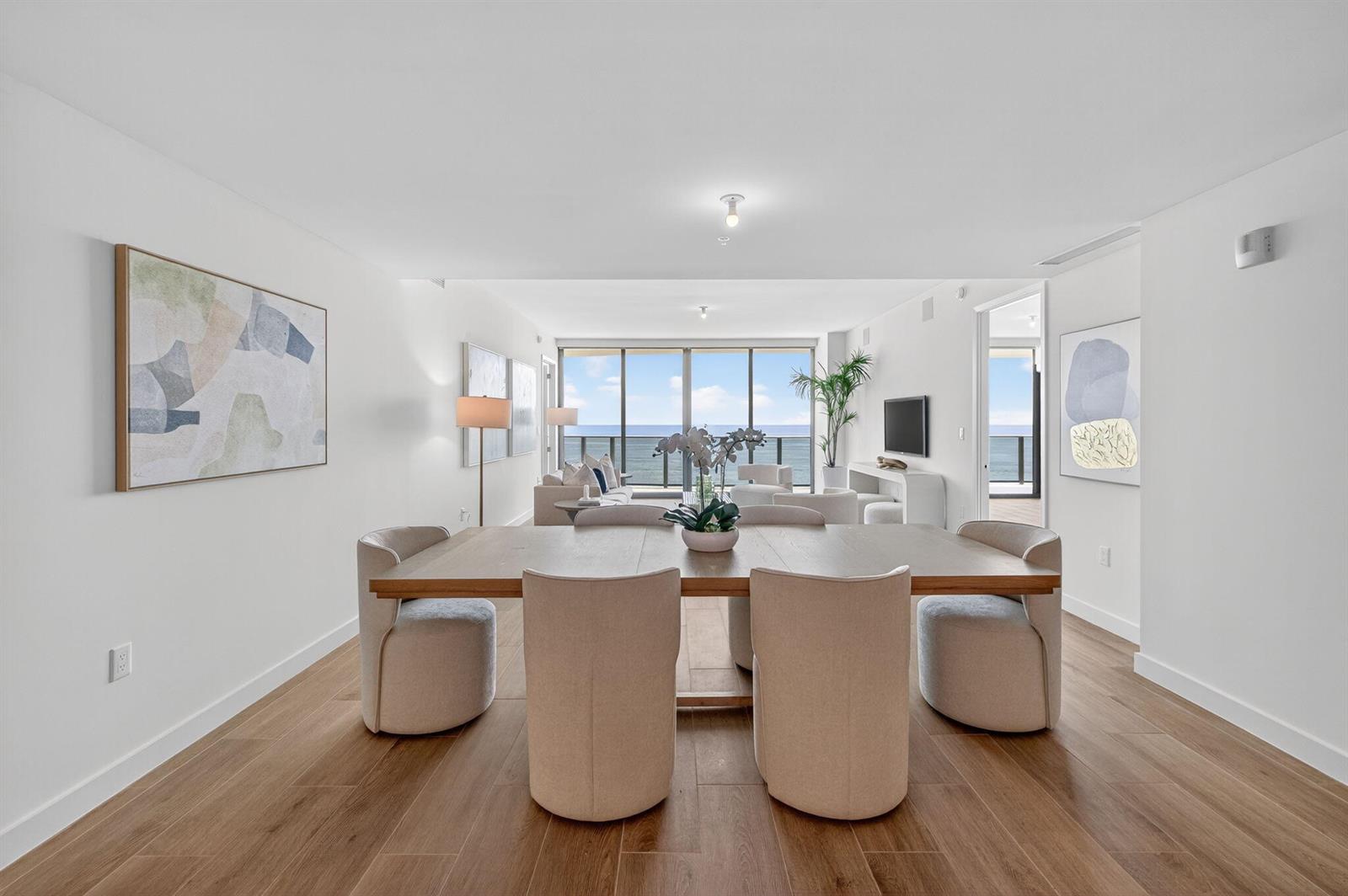 A dining area with a wooden table and upholstered chairs opens to a living room — 900 N Ocean Boulevard # 1702, Pompano Beach FL 33062, POMPANO BEACH, FL