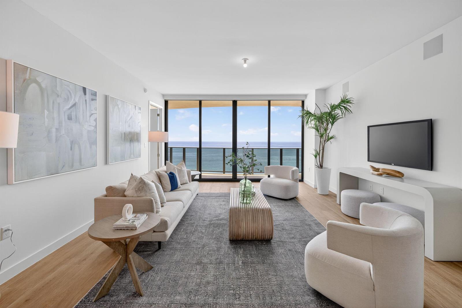 A modern living room features a sofa, armchairs, and floor-to-ceiling windows overlooking the ocean — 900 N Ocean Boulevard # 1702, Pompano Beach FL 33062, POMPANO BEACH, FL