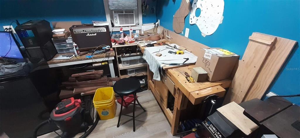 A cluttered workshop features a wooden workbench, a Marshall amplifier, and various tools and materials — 2328 LIMEWOOD AVENUE UNIT 050, CLERMONT, FL