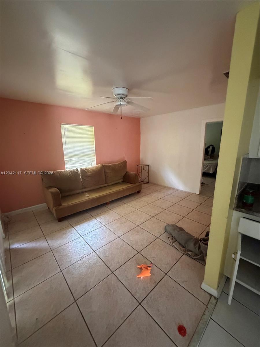 A living room with a tan sofa, tiled floors, a ceiling fan, and pink walls — ROYAL PALM BEACH, FL