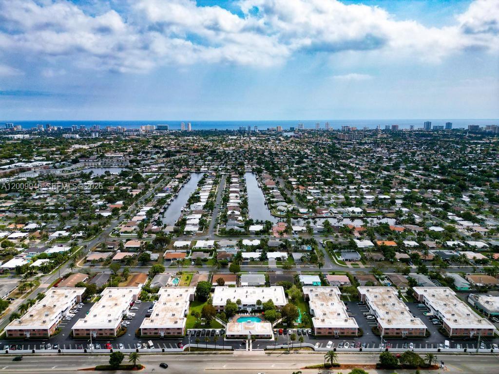 An aerial view shows a residential neighborhood with canals, low-rise apartment buildings, and the ocean — 400 S Cypress Rd # 424, Pompano Beach FL 33060, POMPANO BEACH, FL