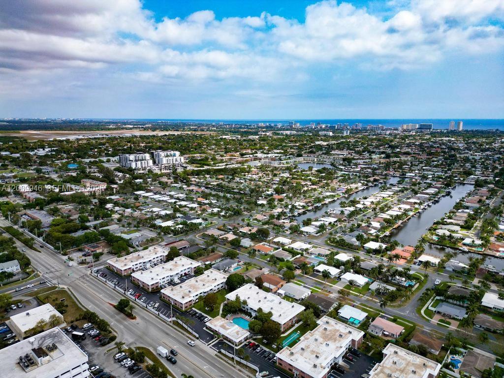 An aerial view shows a suburban neighborhood with apartment complexes, houses, and a canal — 400 S Cypress Rd # 424, Pompano Beach FL 33060, POMPANO BEACH, FL
