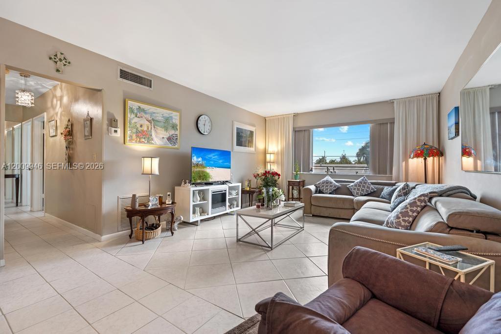 A living room features a sectional sofa, a television on a stand, and tile flooring — 400 S Cypress Rd # 424, Pompano Beach FL 33060, POMPANO BEACH, FL