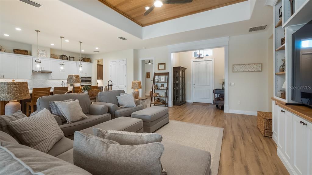 A kitchen features white cabinetry, a large island with four wooden stools, and stainless appliances — 4008 PINNACLE PLACE COURT, LADY LAKE, FL