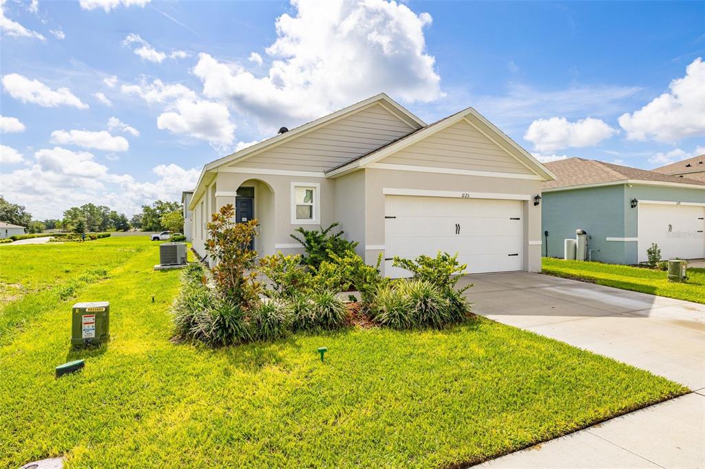 A single-story suburban house with a two-car garage and a front lawn — 1125 BELFAST PLACE, HAINES CITY, FL