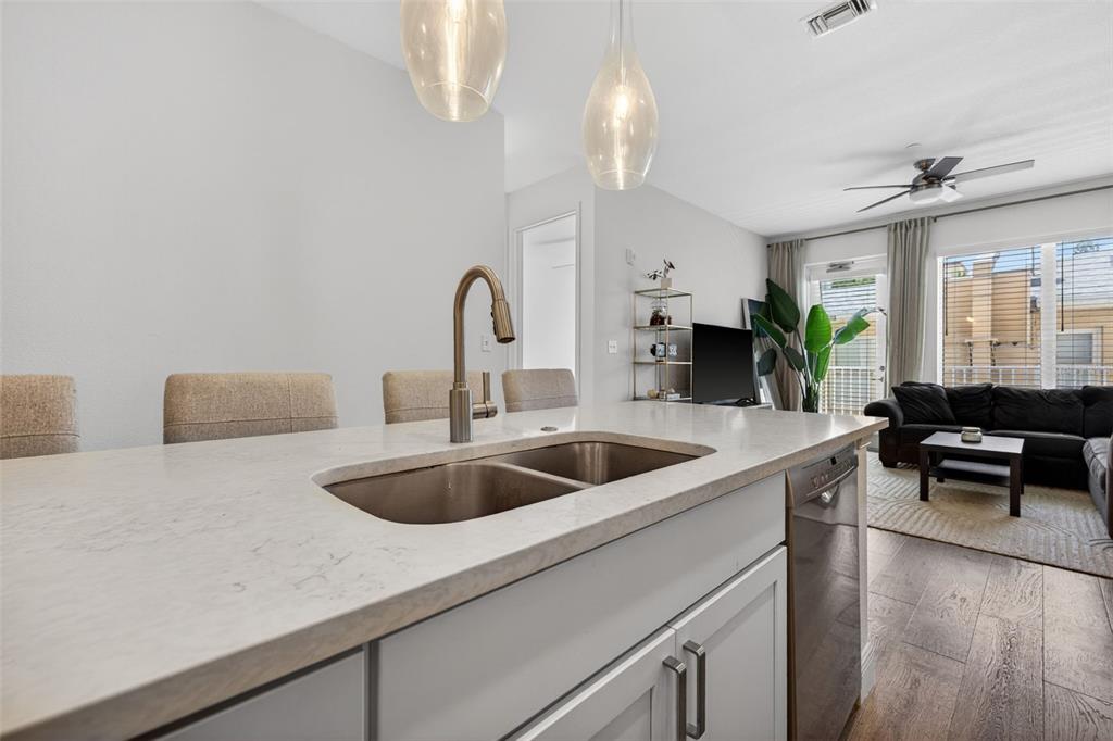 A kitchen island with a double sink and faucet overlooks a living room area — 644 3RD AVENUE S UNIT 202, ST PETERSBURG, FL
