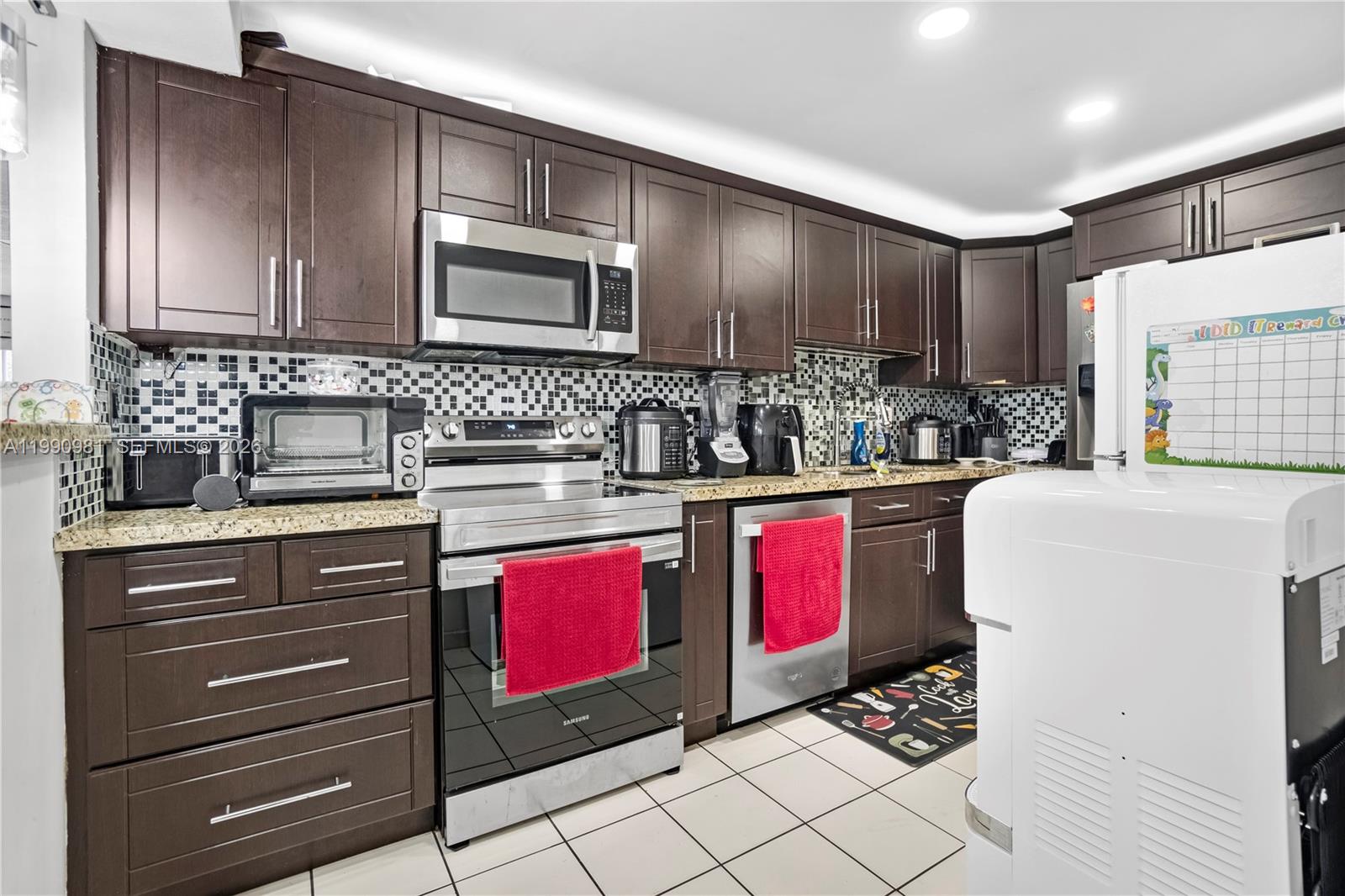 A kitchen features dark wood cabinets, stainless steel appliances, granite countertops, and a tiled backsplash — 9403 SW 76th St # Y17, Miami FL 33173, MIAMI, FL