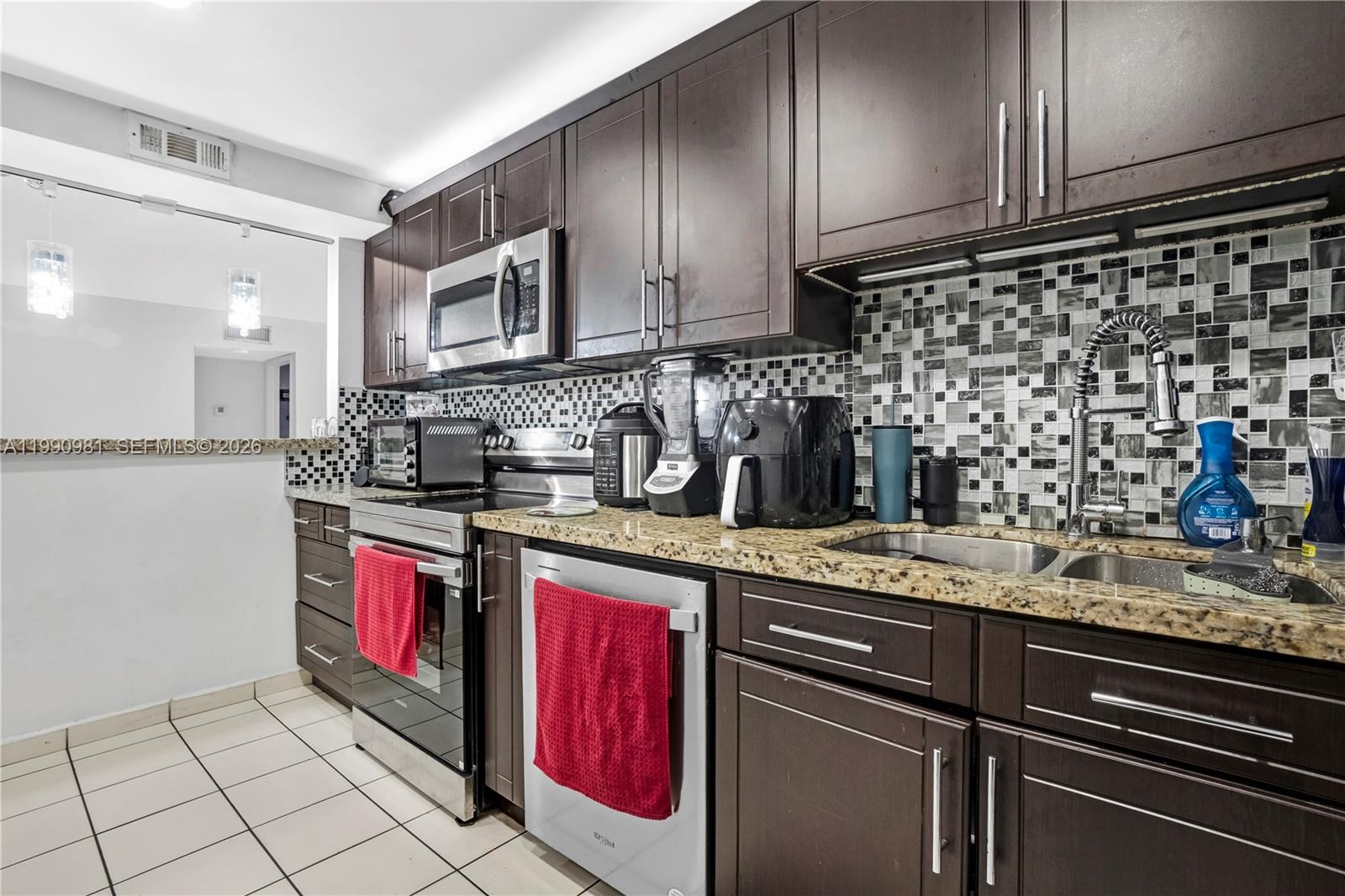 A kitchen features dark wood cabinets, granite countertops, stainless steel appliances, and a mosaic backsplash — 9403 SW 76th St # Y17, Miami FL 33173, MIAMI, FL