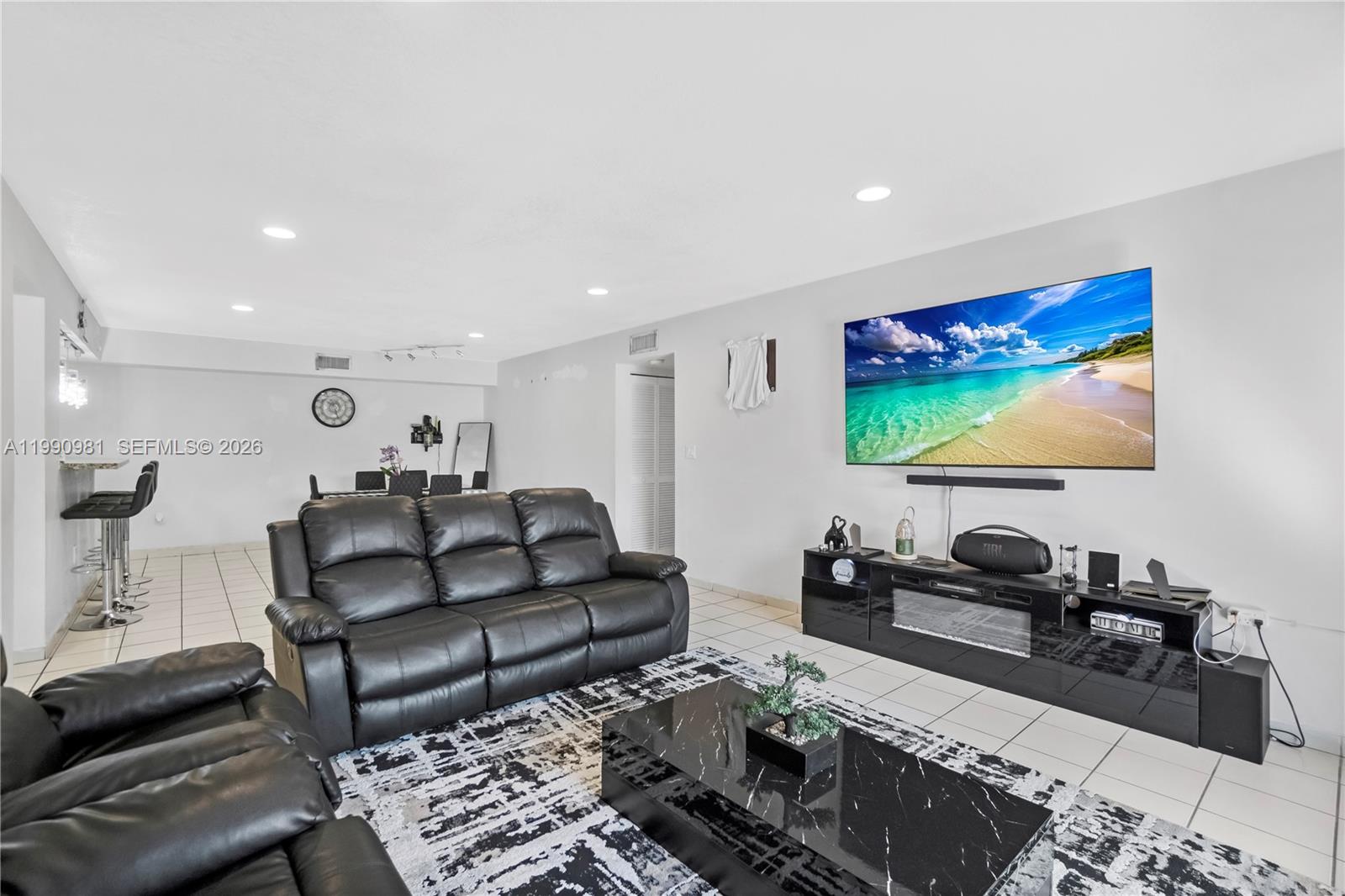A living room features a black leather sofa, a marble coffee table, and a wall-mounted television — 9403 SW 76th St # Y17, Miami FL 33173, MIAMI, FL