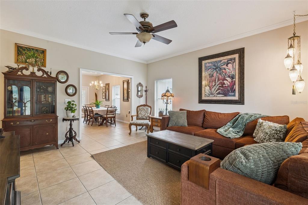 A living room with a brown sectional sofa, tile flooring, and an adjacent dining area — 1411 S PALMETTO AVENUE, SANFORD, FL