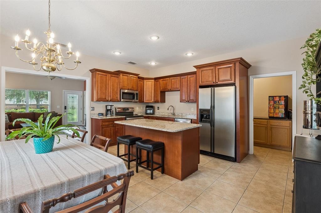 A kitchen with wood cabinets, granite countertops, a center island, and an adjacent dining area — 1411 S PALMETTO AVENUE, SANFORD, FL