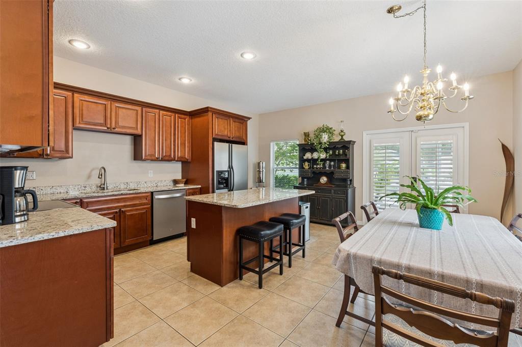 A kitchen with wood cabinets, granite countertops, a center island, and an adjacent dining area — 1411 S PALMETTO AVENUE, SANFORD, FL