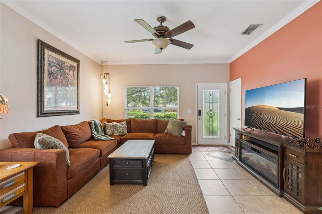 A living room features a brown sectional sofa, a coffee table, and a wall-mounted television — 1411 S PALMETTO AVENUE, SANFORD, FL