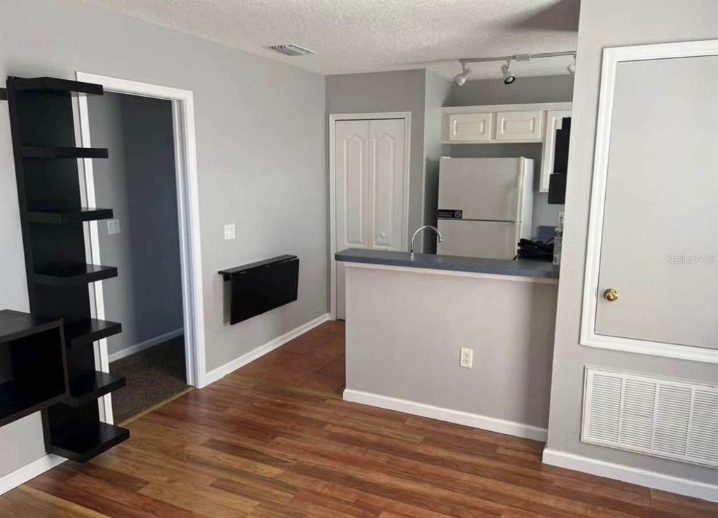 A kitchen with a breakfast bar, white appliances, and wood-look flooring opens to a living area — 3406 MORELYN CREST CIRCLE, ORLANDO, FL