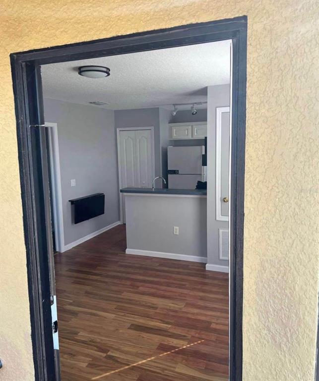 A view through a doorway into a kitchen with wood-look flooring and a breakfast bar — 3406 MORELYN CREST CIRCLE, ORLANDO, FL