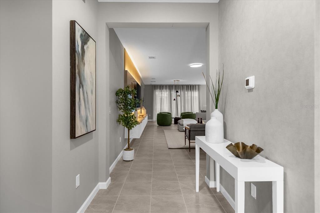 A hallway with tile flooring leads into a living area with modern decor and furniture — 2441 SHANTI DRIVE, KISSIMMEE, FL