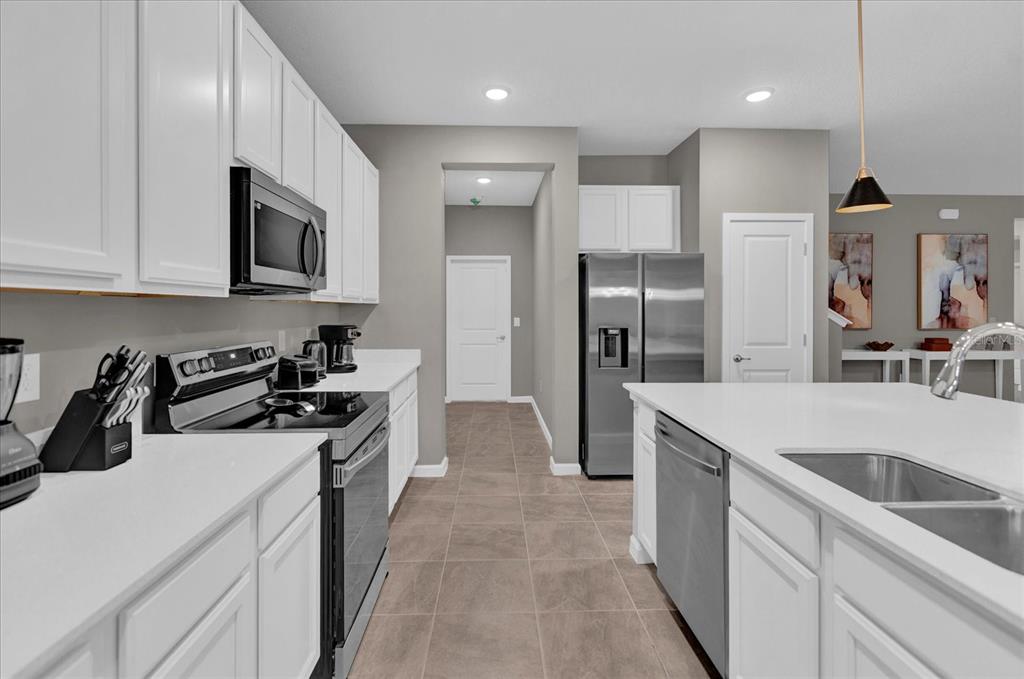 A modern kitchen features white cabinets, stainless steel appliances, and a large central island — 2441 SHANTI DRIVE, KISSIMMEE, FL