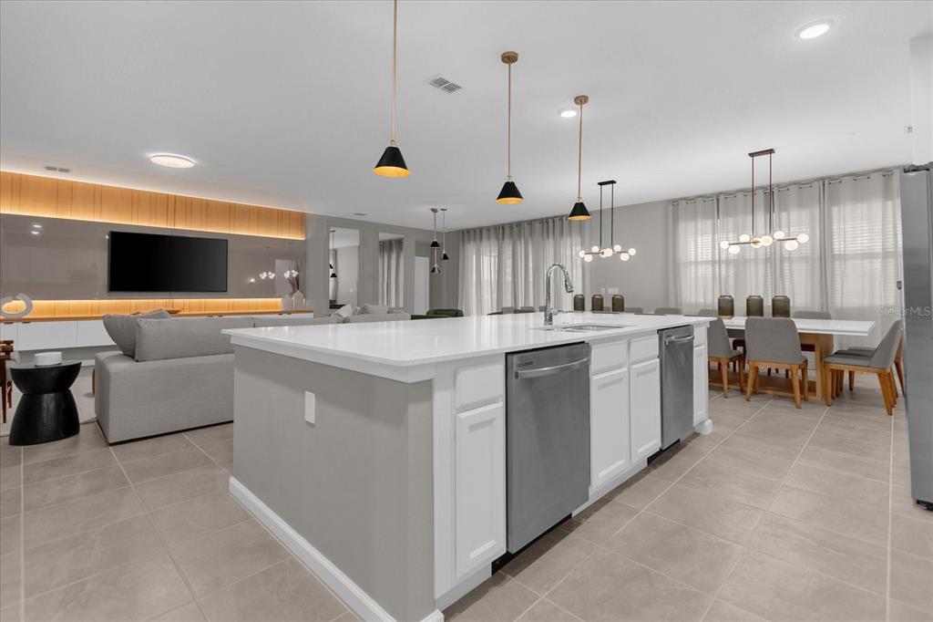 A modern open-concept kitchen features a large white island, stainless steel appliances, and pendant lighting — 2441 SHANTI DRIVE, KISSIMMEE, FL