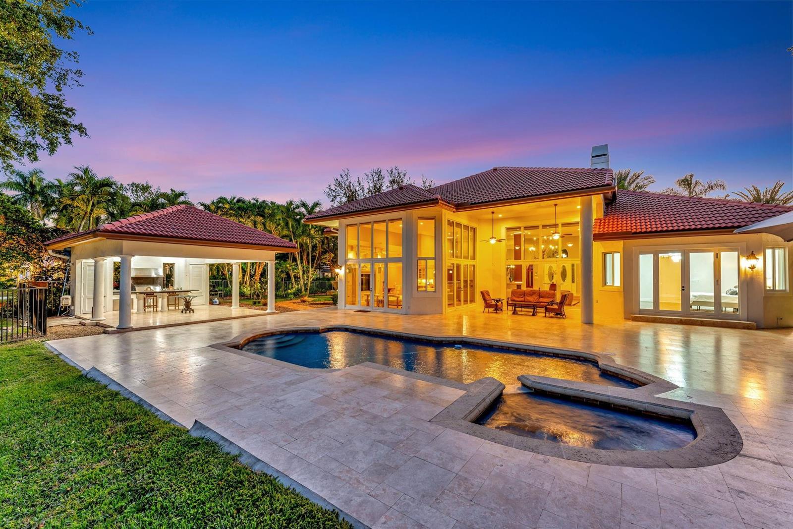 A house exterior at dusk featuring a swimming pool, patio, and a covered outdoor kitchen — 3460 Windmill Ranch Road, Weston FL 33331, WESTON, FL