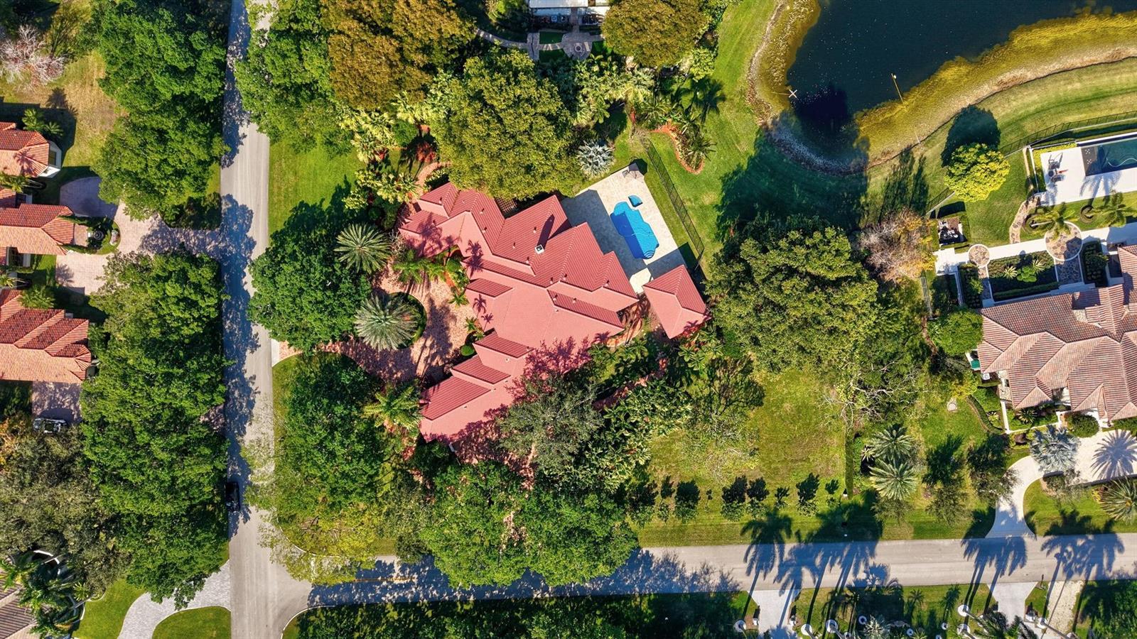 An aerial view shows a house with a red roof, swimming pool, and surrounding trees — 3460 Windmill Ranch Road, Weston FL 33331, WESTON, FL