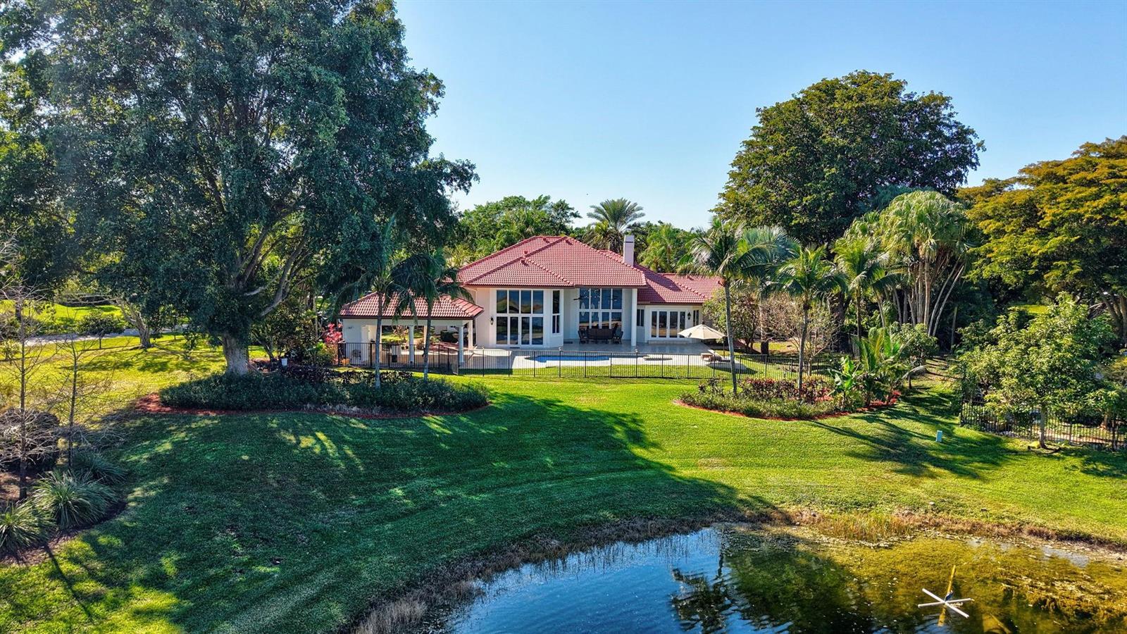 An aerial view of a house with a red tile roof, pool, and surrounding lawn — 3460 Windmill Ranch Road, Weston FL 33331, WESTON, FL